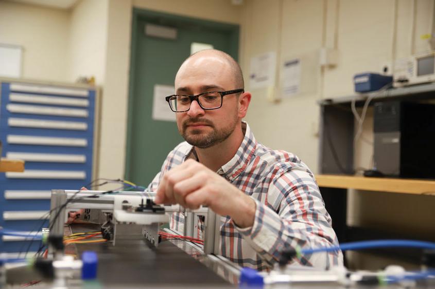 Joseph Cuiffi wiring conveyor belt in lab